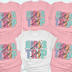 a collection of pink t-shirts with the text "GIRLS TRIP" printed on them.