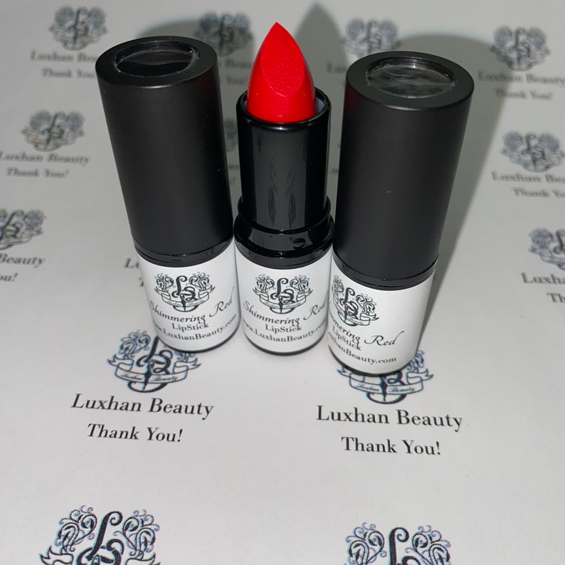 May include: Three black lipstick tubes with a red lipstick bullet. The lipstick is labeled "Shimmering Red Lipstick" and "Luxhan Beauty.com".