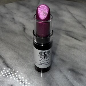 May include: A pink lipstick tube with a silver shimmer finish. The tube is labelled "Lavande Lipstick" and "www.LuxhanBeauty.com".