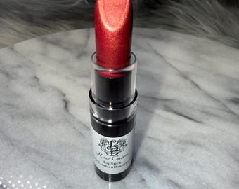 May include: A red lipstick with a gold shimmer in a black tube with a white label that says "Rose Crown Lipstick" and "LashanBeauty.com".