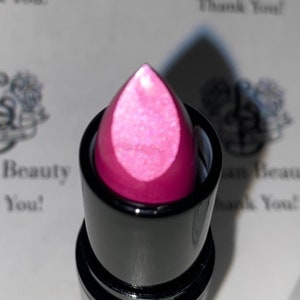 May include: A pink lipstick with a shimmery finish in a black tube.