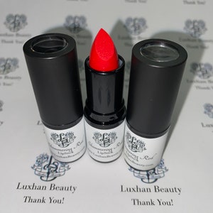 May include: Three black lipstick tubes with clear tops. The middle tube has a red lipstick bullet. The label on the tubes reads "Shimmering Lipstick" and "Luxhan Beauty".