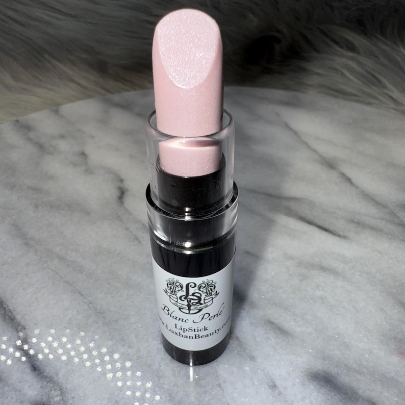 May include: A pink lipstick tube with a black label that reads "Blanc Perle Lipstick LuxhanBeauty.com".