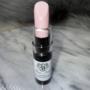 May include: A pink lipstick tube with a clear cap and a black label that reads "Blanc & Perle Lipstick LuxhanBeauty.com".