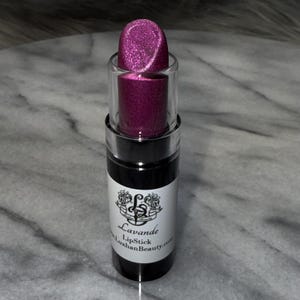May include: A pink lipstick tube with a silver glitter finish. The tube has a black label with the text "Lavande LipStick LuxhanBeauty.com".