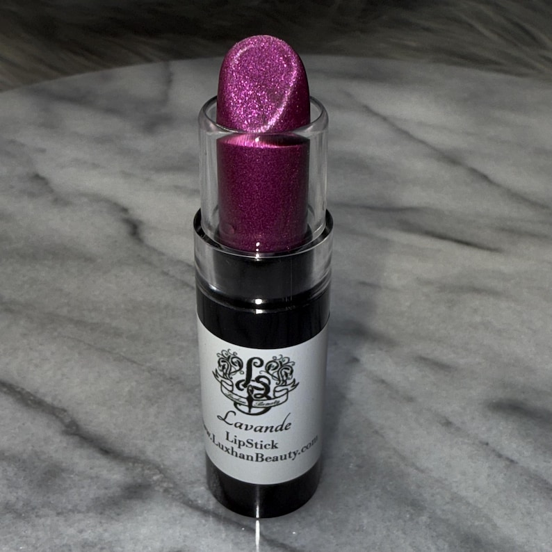 May include: A pink lipstick tube with a silver glitter finish. The tube has a black label with the text "Lavande LipStick LuxhanBeauty.com".