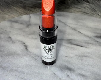 May include: A peach-colored lipstick in a black tube with a silver band. The lipstick is labeled "Peche Lipstick" and "LuxhanBeauty".