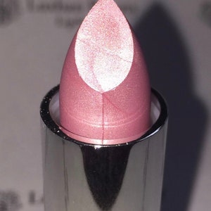 May include: A pink lipstick with a silver tube. The lipstick has a pearlescent finish.