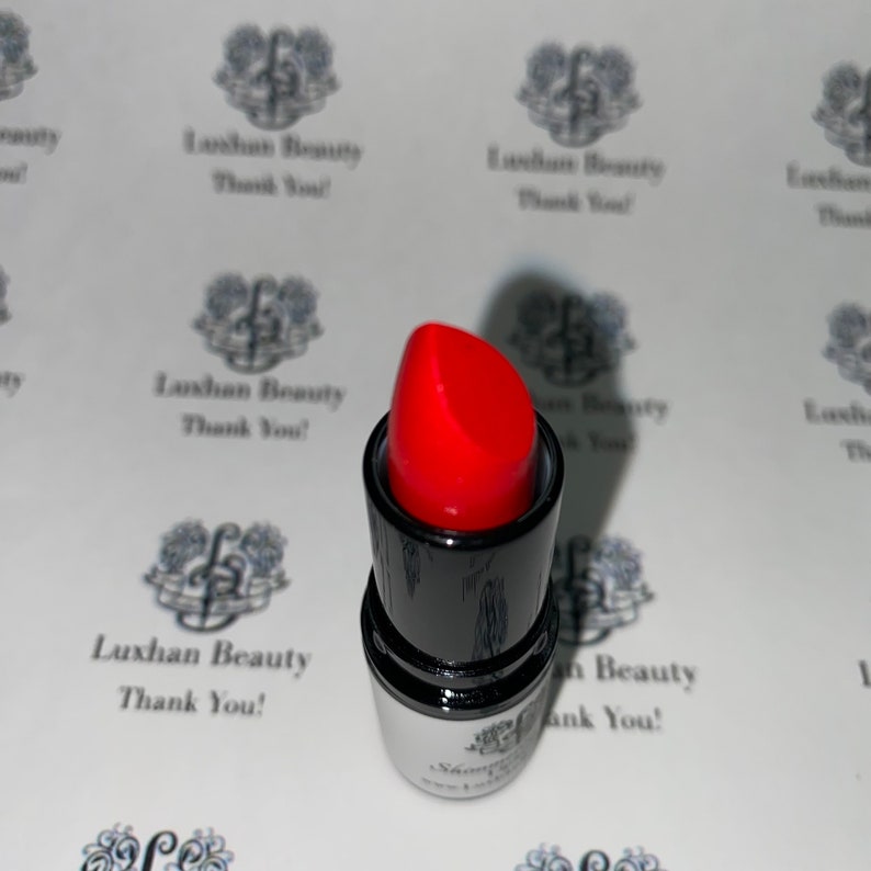 May include: A red lipstick in a black tube with a white label. The label has the text "Luxhan Beauty Thank You!" printed on it.