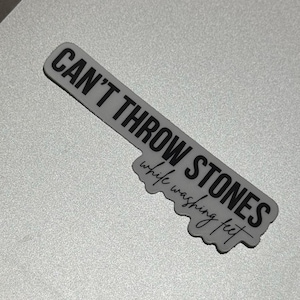 May include: White sticker with black text that reads "Can't throw stones while washing feet."