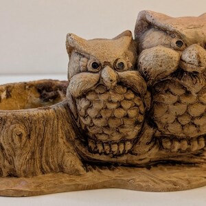 May include: A detailed, brown owl planter with two owl figures perched beside a small, open container. The owls have textured feathers and large eyes. The planter is designed to resemble a tree stump, adding a rustic touch to the decor.