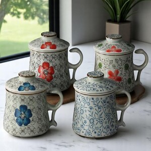 May include: Four ceramic mugs with lids, each featuring a different floral pattern. The mugs are white with blue and red floral designs. The lids have a small opening for sipping.