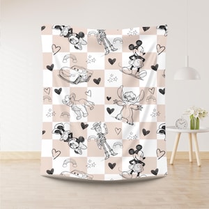 May include: A white and tan checkered blanket featuring cartoon characters like Mickey Mouse, Minnie Mouse, Stitch, and Simba. The blanket has black hearts, rainbows, and stars scattered throughout the design.