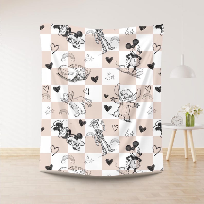 May include: A white and tan checkered blanket featuring cartoon characters like Mickey Mouse, Minnie Mouse, Stitch, and Simba. The blanket has black hearts, rainbows, and stars scattered throughout the design.