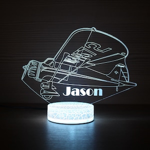 以下が含まれることがあります： 「Jason」の名前が入った、飛行機型のパーソナライズされたLEDナイトライト。ヴィンテージ航空機の詳細なアウトラインが特徴です。ベースは丸く、パターン化されたデザインで、柔らかな光を放ちます。