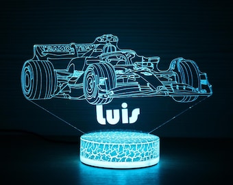 May include: A blue LED night light featuring a Formula 1 race car design. The car is illuminated with a neon effect, and the name "Luis" is displayed below the car. The base has a cracked pattern.