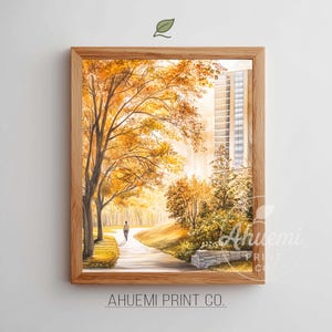 May include: Watercolor painting of a park scene in autumn. A person walks down a path lined with trees in shades of yellow and orange. A building is visible in the background. The artwork is framed in a light brown wooden frame.