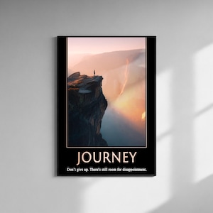 Könnte beinhalten: A framed poster with a landscape image of a person on a cliff edge. The poster has the word "JOURNEY" in white text at the bottom, with the text "Don't give up. There's still room for disappointment."
