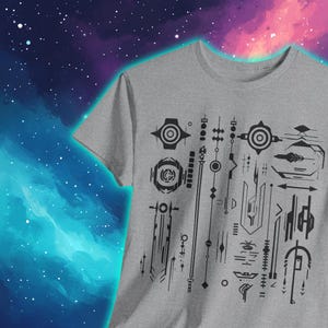 Puede incluir: Una camiseta gris con un diseño geométrico negro que presenta círculos, líneas y flechas. El diseño se asemeja a un patrón futurista o tecnológico.