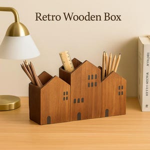 Peut inclure: Un organiseur de bureau en bois marron en forme de maisons. Il contient des crayons, une règle et d'autres articles de papeterie. Le texte "Retro Wooden Box" est affiché en haut.