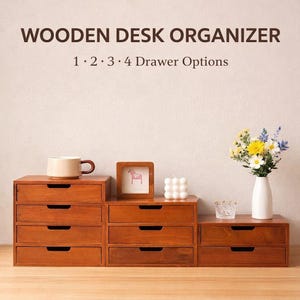 Puede incluir: Organizadores de escritorio de madera con opciones de 1, 2, 3 o 4 cajones. Los organizadores son de madera y tienen un acabado marrón cálido. Una taza, un cuadro enmarcado, una vela y un jarrón con flores están encima.