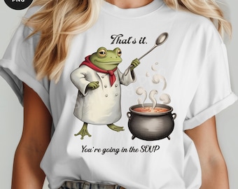 May include: White t-shirt featuring a cartoon frog chef with a red scarf, holding a spoon over a bubbling pot of soup. Text reads "That's it." and "You're going in the SOUP."