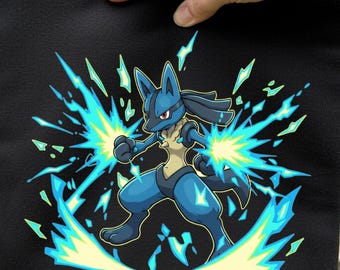 Könnte beinhalten: Schwarze quadratische Tasche mit einer blau-gelben Cartoonfigur, die von Energieexplosionen umgeben ist. Die Figur befindet sich in einer Kampfhaltung, mit blauen und gelben Energieeffekten. Die Tasche wird von einer Hand gehalten.