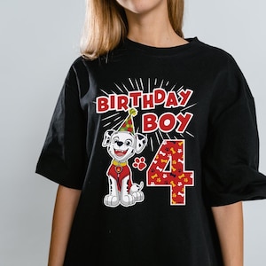 May include: Black t-shirt featuring a cartoon Dalmatian wearing a party hat and a red vest. The text "BIRTHDAY BOY" is above the dog, and the number "4" is printed in red with a paw print pattern.