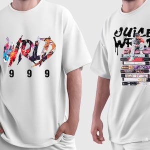 May include: Two white t-shirts with graphic designs. One shirt features the word "WORLD" in a colorful, collage-style design with the numbers "999" below. The other shirt displays "JUICE WRLD" in black graffiti-style lettering above a stack of cassette tapes.