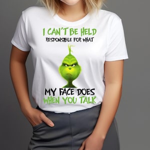 May include: White t-shirt featuring a green Grinch graphic with the text "I CAN'T BE HELD RESPONSIBLE FOR WHAT MY FACE DOES WHEN YOU TALK." The Grinch has an angry expression. The shirt is a short-sleeved crew neck.