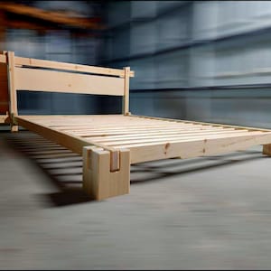 May include: A wooden bed frame with a slatted base and a simple headboard. The frame is made of unfinished pine wood and has a natural wood finish.