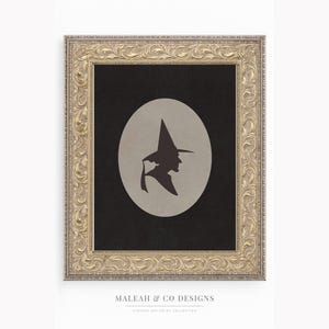 May include: Framed art print featuring a witch silhouette in a pointed hat against a gray oval on a black background. The print is in a gold ornate frame. The text "MALEAH & CO DESIGNS" is at the bottom.