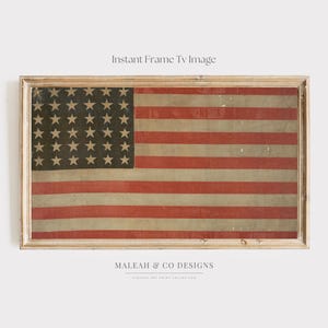 May include: A framed vintage American flag print. The flag features red and white stripes with a field of dark stars. The print is in a light-colored wooden frame. The text "Instant Frame TV Image" is at the top.