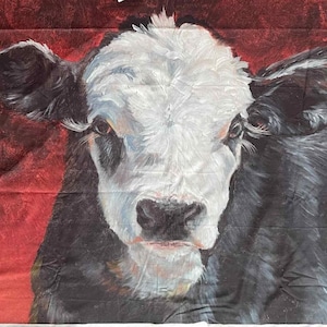 May include: A fabric print featuring a cow's face. The cow has a white face with black patches and a red background. The cow's eyes are focused forward. The artwork is a close-up of the cow's face.