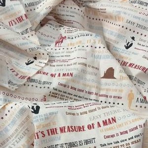 May include: Off-white fabric with a repeating text and graphic design. The text includes phrases like "It's the measure of a man" and "Daylight." The design features cowboy and silhouette illustrations in red, brown, and black.