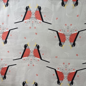 May include: Gray fabric with a repeating pattern of stylized birds. Each bird is black, red, and yellow, with geometric wings and a symmetrical design. The background has small red and white accents.