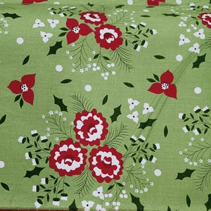 Può includere: Un tessuto verde salvia con un motivo ripetitivo di grappoli floreali rossi e bianchi, foglie di agrifoglio verde scuro e piccole bacche bianche. Il design include sottili linee verdi e puntini bianchi sparsi sulla superficie.