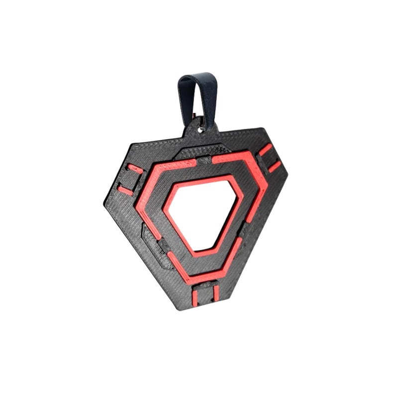 May include: Black and red geometric pendant with a dark blue loop. The pendant has a layered design with a central open shape. The red accents create a striking contrast against the black.