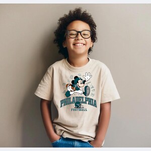 A young boy wearing glasses and a Philadelphia Eagles t-shirt is smiling and posing for the camera.
