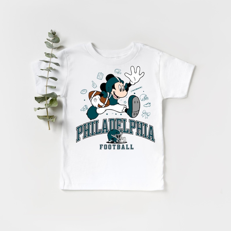 A white t-shirt with a graphic design featuring a cartoon character and text related to Philadelphia Football.