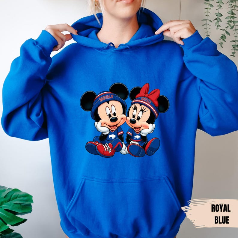 A person wearing a blue hoodie with a graphic of two cartoon mice, one wearing a baseball cap and the other a bow, sitting together.
