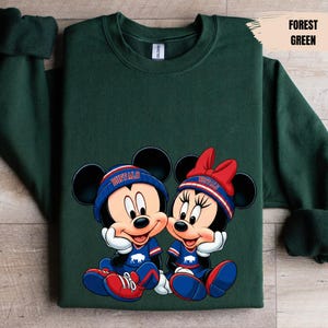 A green sweatshirt with a graphic of two cartoon mice wearing sports gear and the word " buffalo" on their hats.