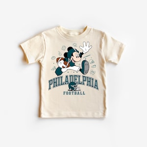 A white t-shirt with a graphic design featuring a cartoon character and text related to Philadelphia Football.