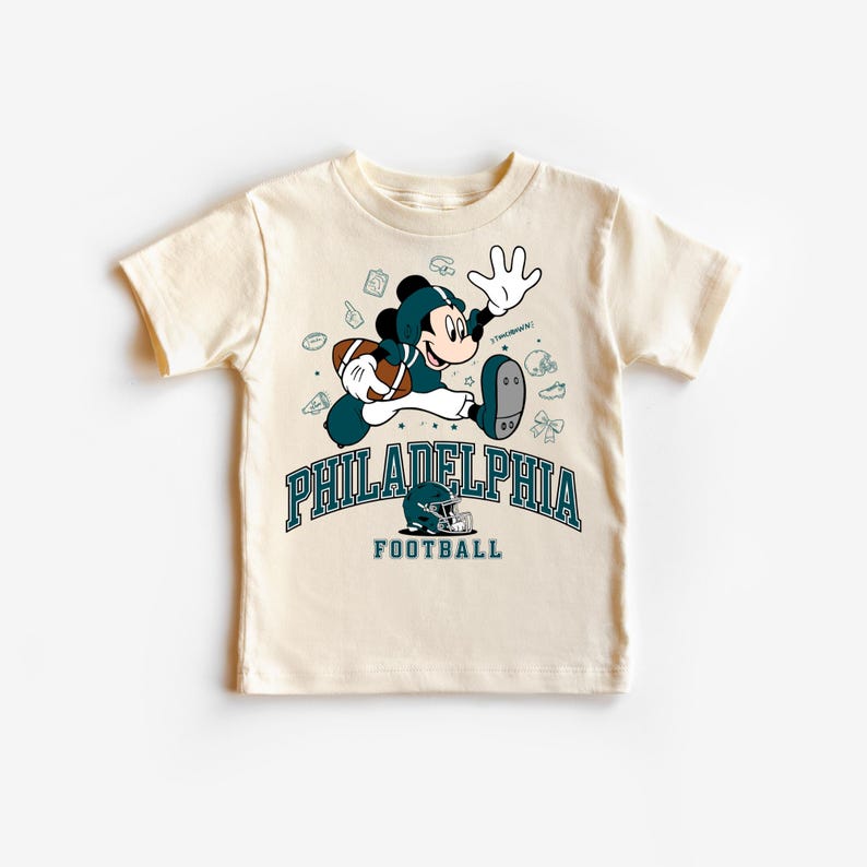 A white t-shirt with a graphic design featuring a cartoon character and text related to Philadelphia Football.