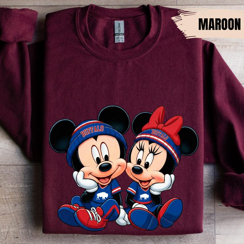 A maroon t-shirt with a graphic design featuring two cartoon mice, one male and one female, wearing matching outfits and accessories.