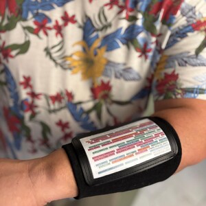May include: Black arm band with a clear plastic window displaying a colorful chart with text. The chart is labeled "Color Code" and lists various colors with corresponding numbers.