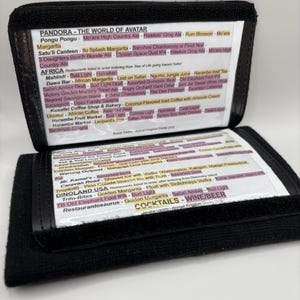 May include: A black wallet-style card holder with a white background and pink, red, and yellow text. The card holder lists the drinks and food available at the Pandora - The World of Avatar theme park at Disney World.
