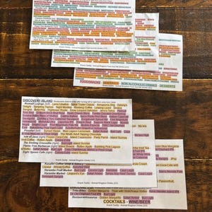 May include: A stack of printed menus on a wooden table. The menus feature a variety of food and drink options, with text in multiple colors. The menus are for a restaurant or bar, with categories like "Food/Snacks" and "Cocktails/Wine/Beer."