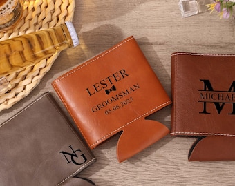 May include: Three leather drink holders in shades of brown. One is tan with the name "LESTER", the word "GROOMSMAN", and the date "05.06.2025". Another is dark brown with the name "MICHAEL". The third is gray with the initials "NG".