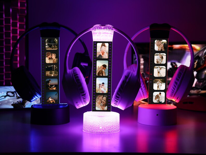 May include: Three personalized photo lamps with wireless headphones. Each lamp displays a strip of photos and sits on a base. The lamps are illuminated with purple and white light, creating a romantic ambiance. The headphones are white and purple.